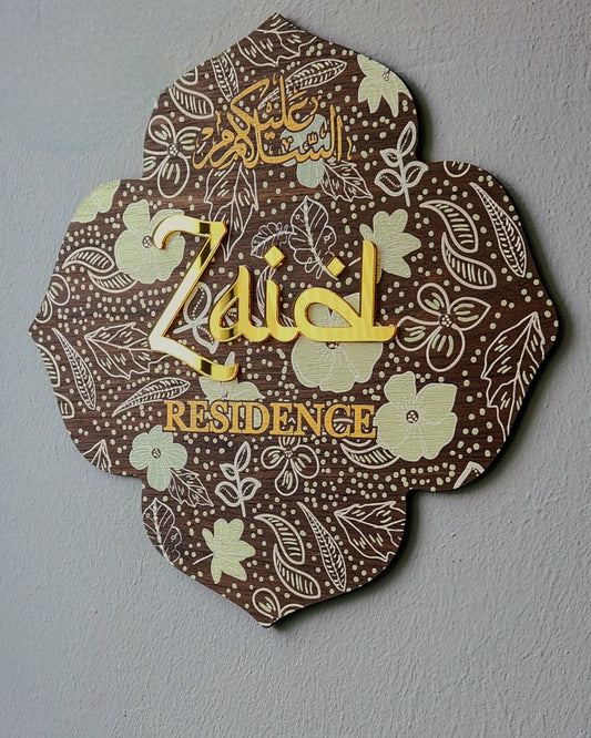 A decorative plaque with a floral and geometric pattern, featuring the name 'Zaid' in an ornate font, mounted on a wall.