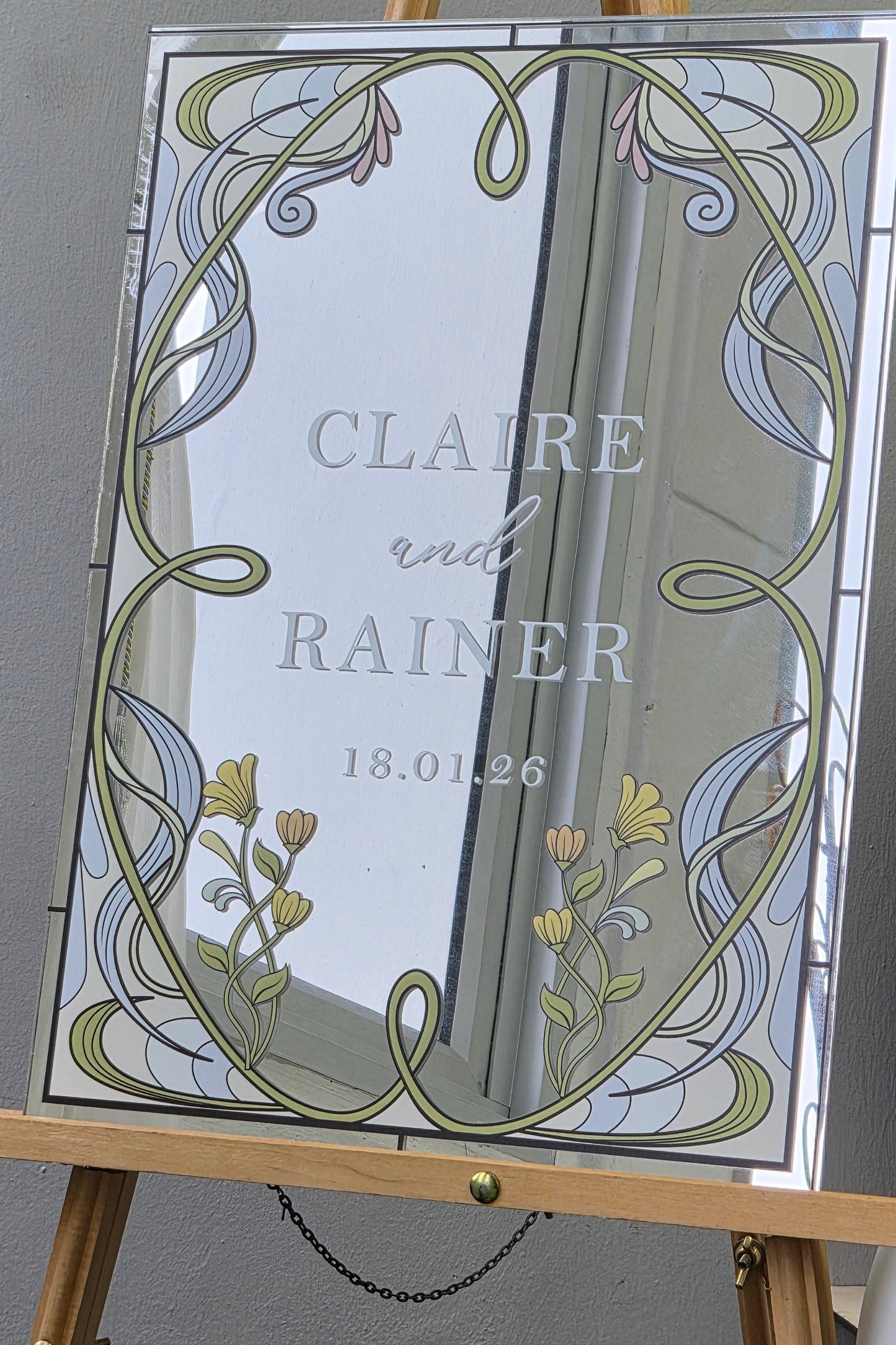 Decorative acrylic panel with floral design and couples names on a stand.