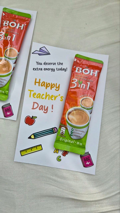 A Teacher's Day greeting card featuring a BOH 3in1 instant coffee packet illustration, with 'Happy Teacher's Day!' written in yellow text, displayed on a light fabric surface.