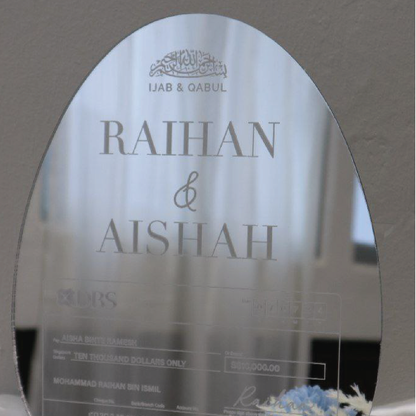 Decorative mirror with engraved text and branding on a gray background